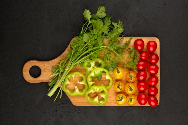 Foto gratuita vista dall'alto verdure affettate e intere come il peperone verde giallo pomodori rossi su sfondo scuro