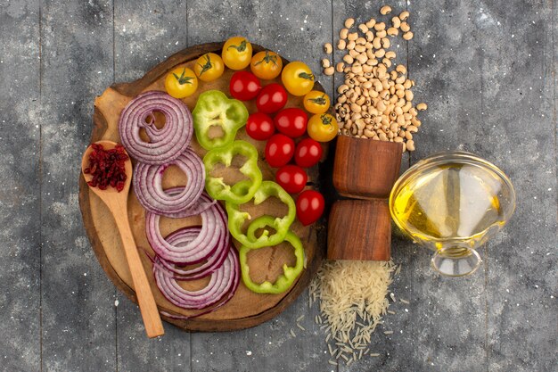 top view vegetables sliced and whole such as onions tomatoes on the brown desk and grey wooden rustic background