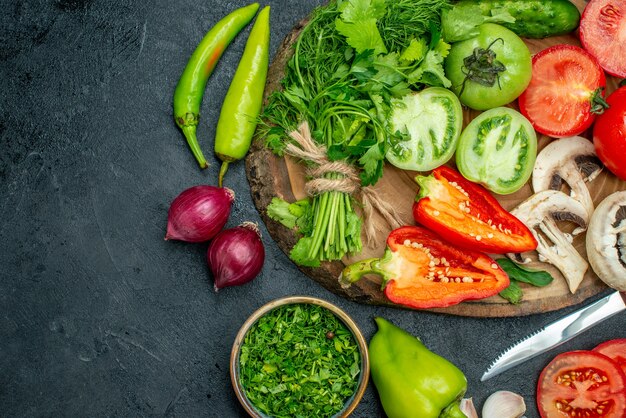 Top view vegetables tomatoes bell peppers cucumber greens mushroom on wood board