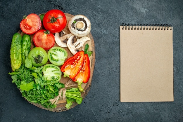 Top view vegetables tomatoes bell peppers cucumber greens mushroom on wood board