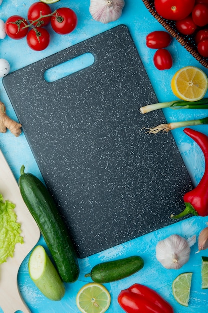 Top view of vegetables with cutting board on blue surface