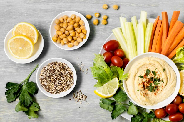 Top view of vegetables with hummus and lemons