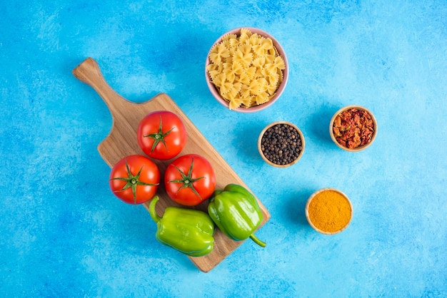 Foto gratuita vista dall'alto. verdure su tavola di legno e spezie con pasta cruda sulla superficie blu.