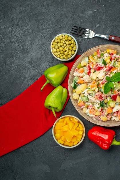 Top view of veggie salad on red napkin and with veggies and fork on side on dark grey background