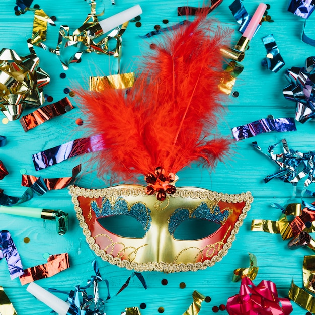 Vista dall'alto della maschera di carnevale veneziano con piuma in oro e rosso con materiale per la decorazione del partito