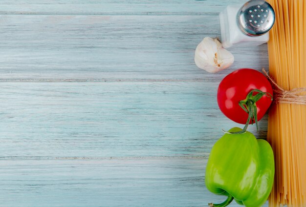 Top view of vermicelli macaroni with tomato pepper garlic and salt on wooden surface with copy space