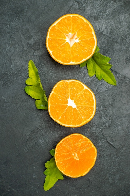 Top view vertical row cut oranges on dark surface