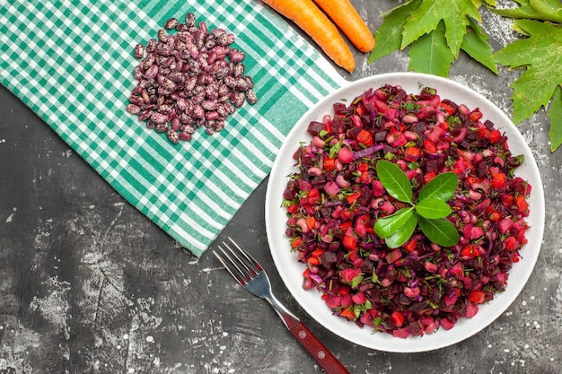 Top view vinaigrette salad with beet and beans on dark surface