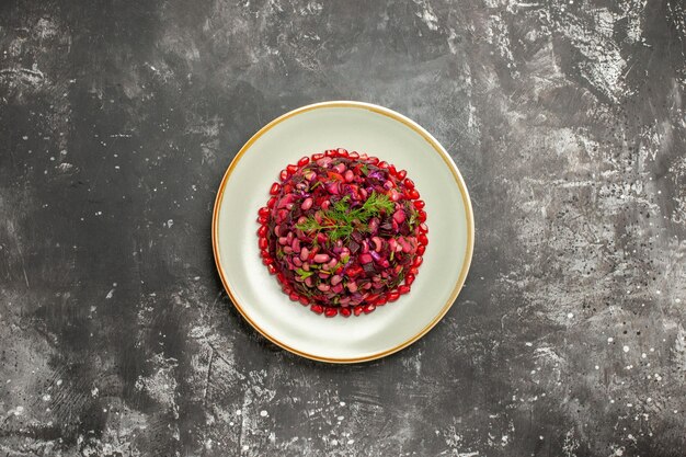 Top view vinaigrette salad with pomegranates and beans on a grey surface