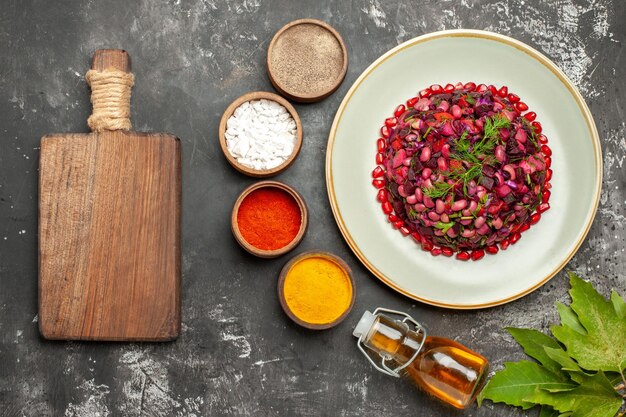 Top view vinaigrette salad with seasonings on dark surface