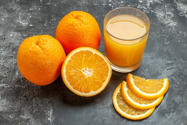 Top view of vitamin source cut chopped and whole fresh oranges and juice on gray background