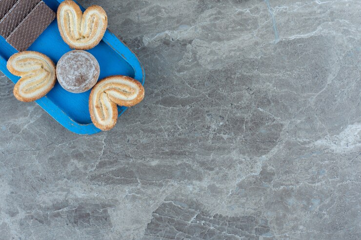 मुफ़्त फोटो top view of wafers and cookies on blue wooden plate.