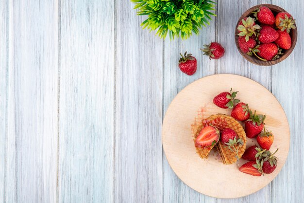 와플 비스킷과 딸기 커팅 보드와 그릇 및 나무 표면에 상위 뷰