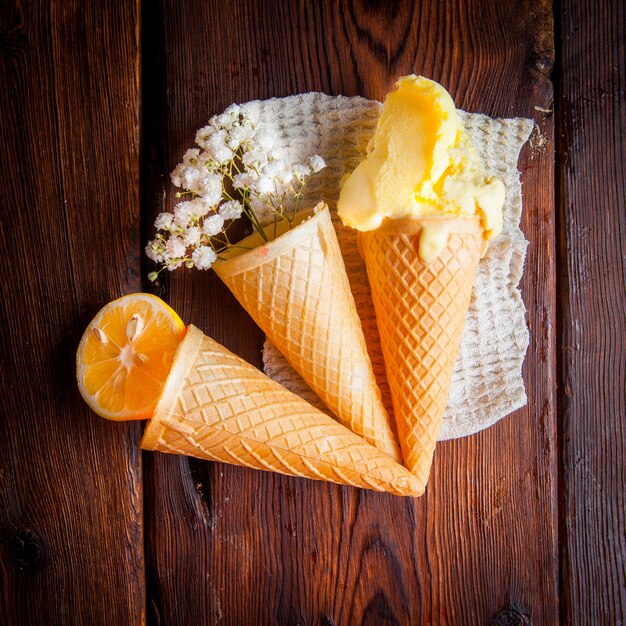Top view waffle cones with ice cream and orange and gypsophila in rag napkins