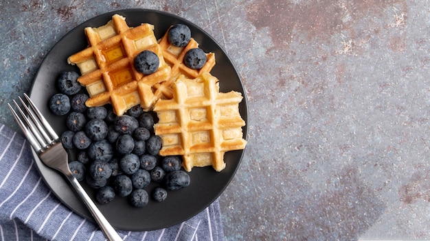 Top view of waffles and blueberries on plate with fork and copy space