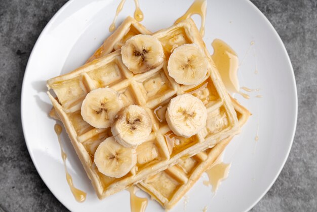Top view of waffles on plate with honey and banana slices