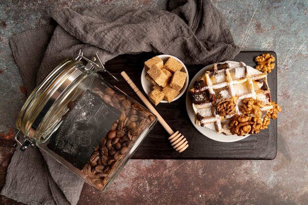 Top view of waffles stacked on plate with walnuts and sugar cubes