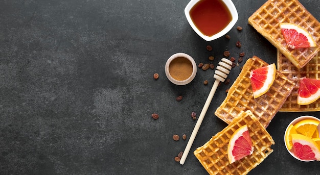 Top view of waffles with honey dipper and fruit