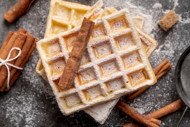 Top view of waffles with powdered sugar and cinnamon sticks