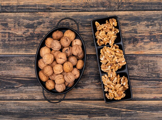 Top view walnuts in a basket and plate on wooden  horizontal