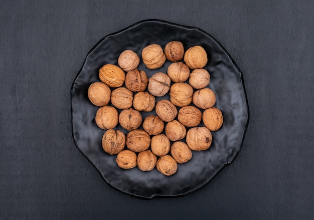 Top view walnuts in black plate on black  horizontal