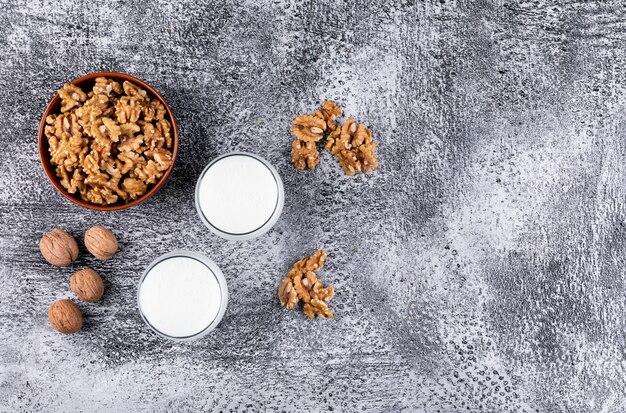 Вид сверху грецкие орехи в миску и стакан молока на камне горизонтальной