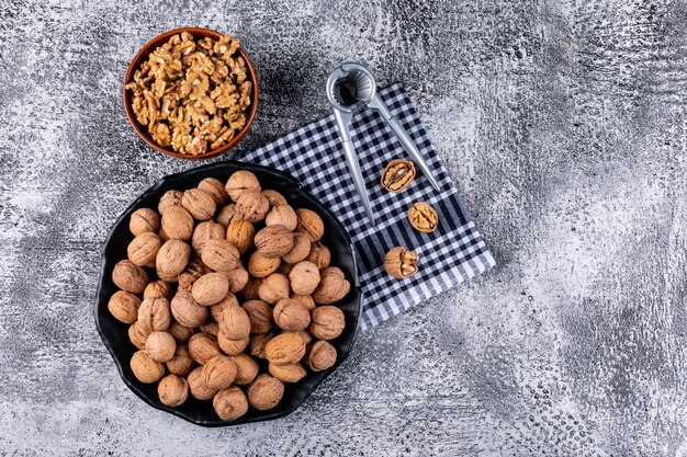 Free photo top view walnuts in bowl and nutcracker on stone  horizontal