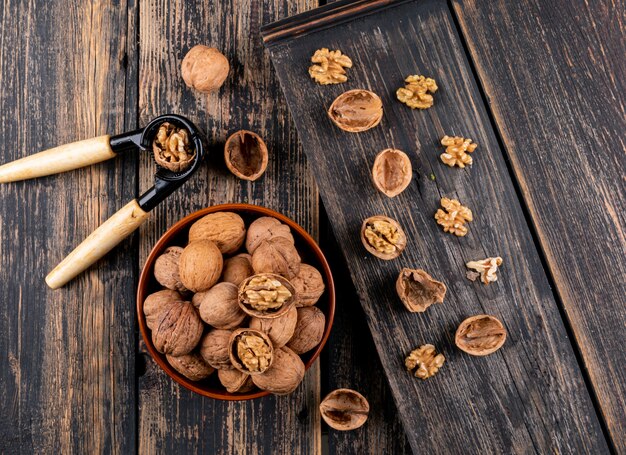 Вид сверху грецкие орехи в миску и Щелкунчик на деревянной горизонтали