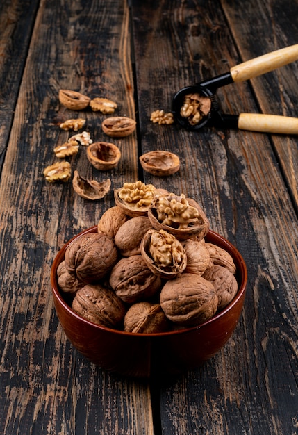 Top view walnuts in bowl and nutcracker on wooden  vertical