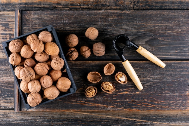 Top view walnuts and nutcracker in black box on wooden  horizontal