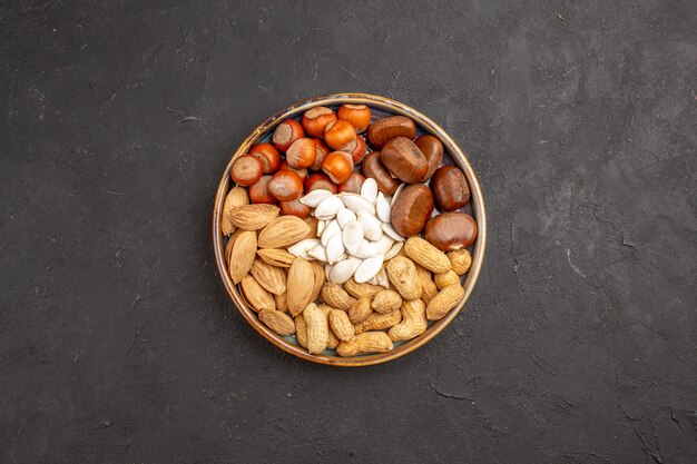 Top view of walnuts, peanuts, hazelnuts and others on a dark surface