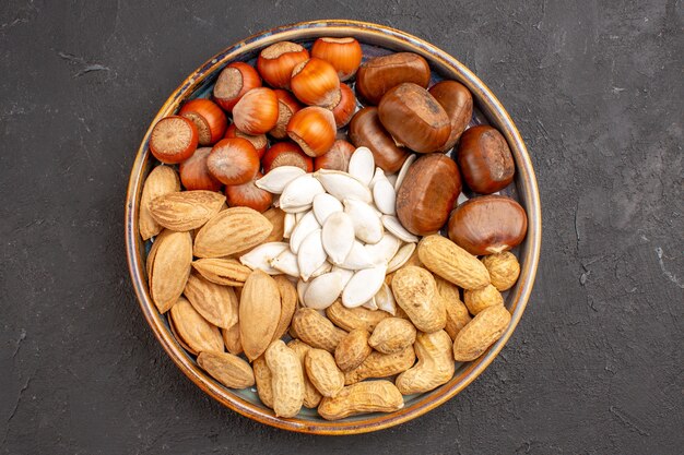 Top view of walnuts, peanuts, hazelnuts and others on dark surface