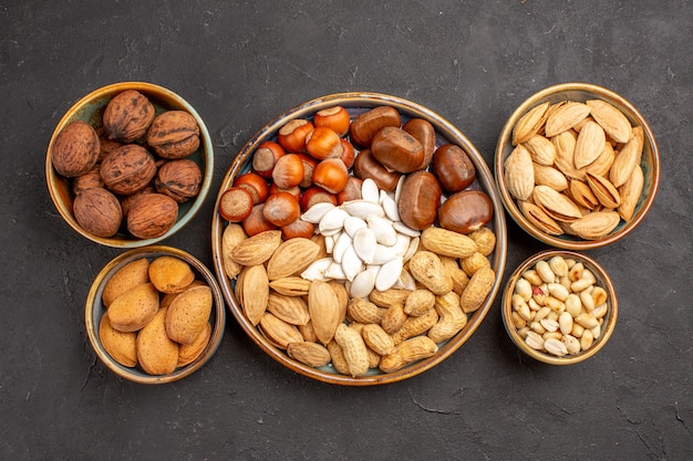 Top view of walnuts, peanuts, and other nuts on a dark surface