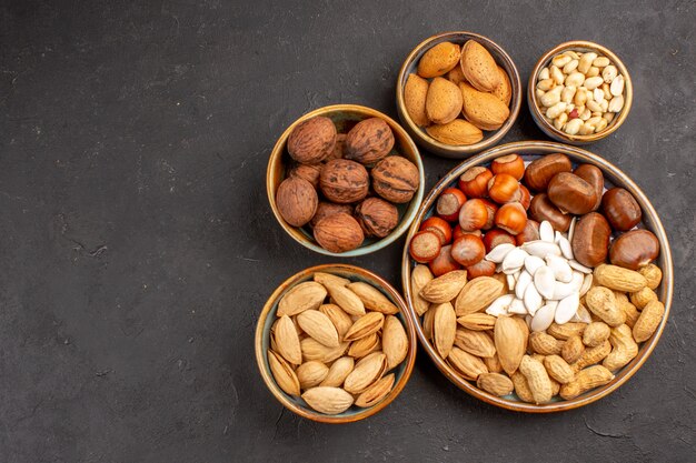 Top view of walnuts, peanuts, and other nuts on dark surface