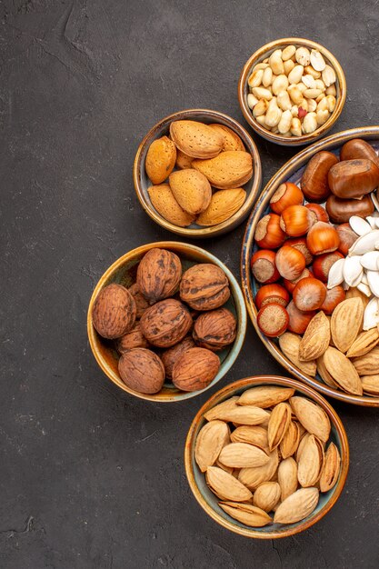 Top view of walnuts, peanuts, and other nuts on dark surface