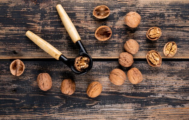 Free photo top view walnuts with nutcracker on wooden  horizontal