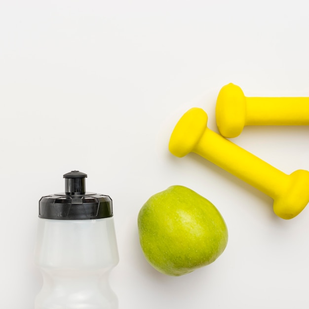 Top view of water bottle with apple and weights