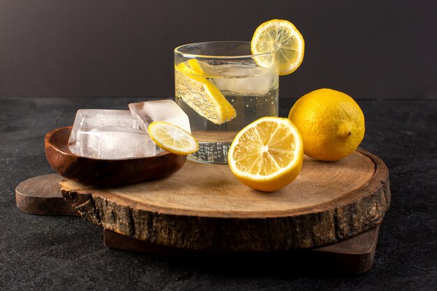 A top view water with lemon fresh cool drink inside glass with ice cubes with sliced lemons on the dark background cocktail drink fruit