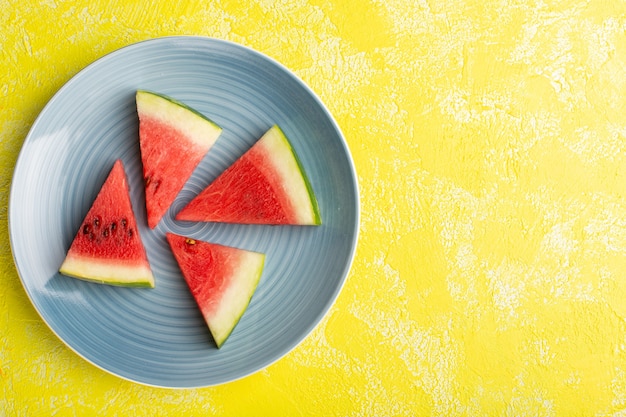 Free photo top view of watermelon slices inside blue plate on the yellow surface
