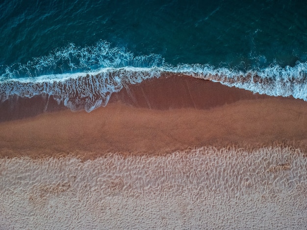 Top view of waves on the sandy beach on Crete island