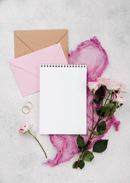 Top view wedding rings with flowers and envelopes