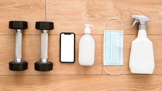 Top view of weights with cleaning solution and smartphone for gym