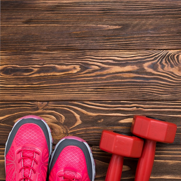 Top view of weights with sneakers on wooden background