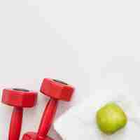 Free photo top view of weights with towel and apple