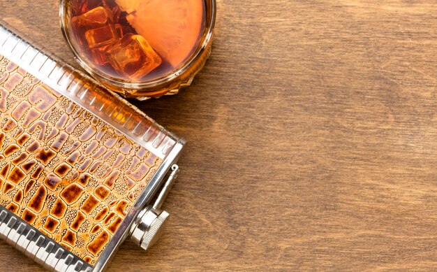 Top view whiskey on the rocks and flask with copy-space