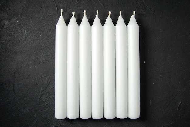 Top view of white candles on the dark wall