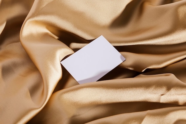 Вид сверху белая карточка на золотой ткани