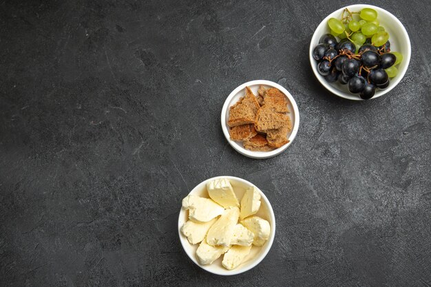 暗い表面のフルーツフードミルクミールパンに新鮮なブドウとトップビューホワイトチーズ