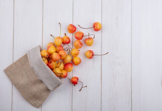 Top view white cherry in a burlap bag on a white table