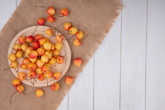 Top view of white cherry on a stand on a beige napkin on a white surface